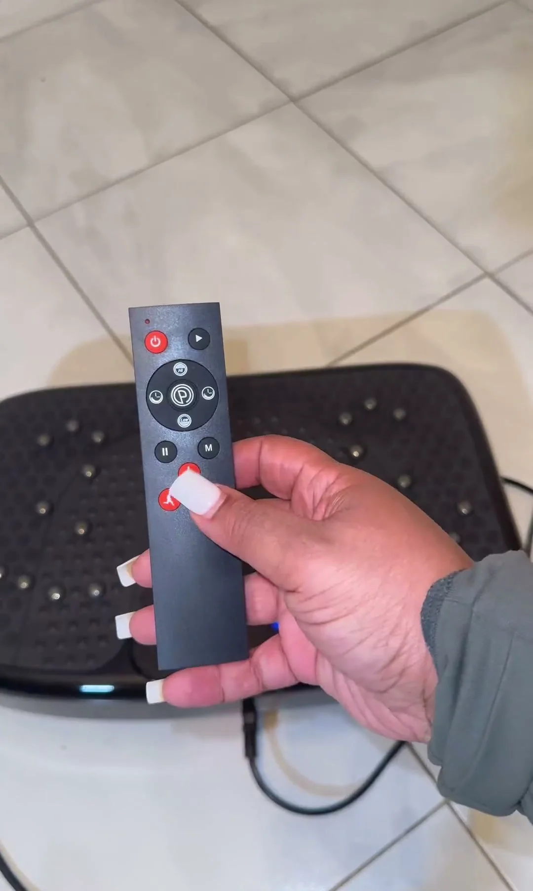 A hand holding the SoftGym remote over the plate