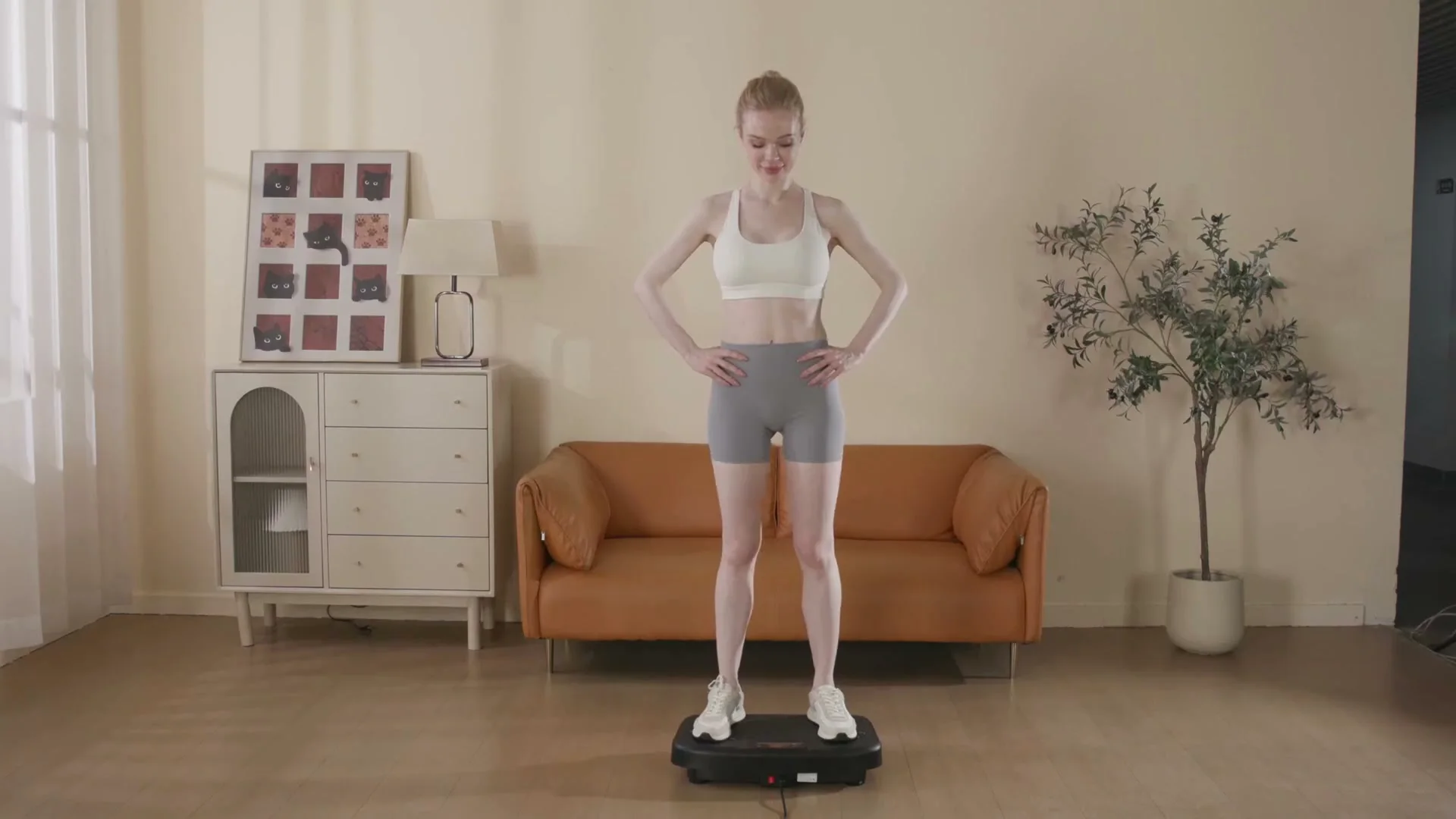 A woman standing on a black SoftGym plate in a living room